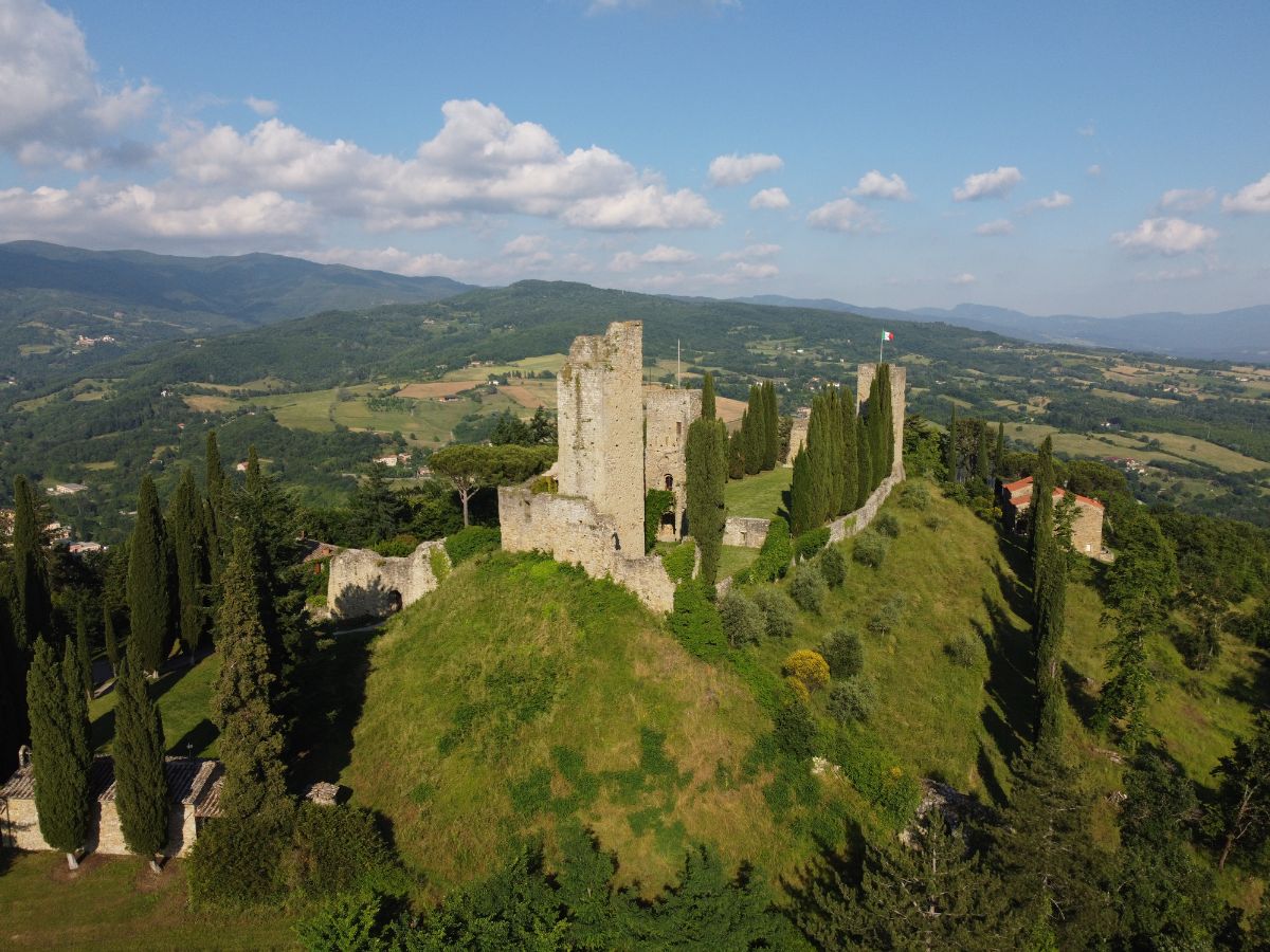 Veduta aerea del Castello di Romena con i suoi cipressi e le sue torri in pietra situate in cima a una verde collina che domina la valle del Casentino.