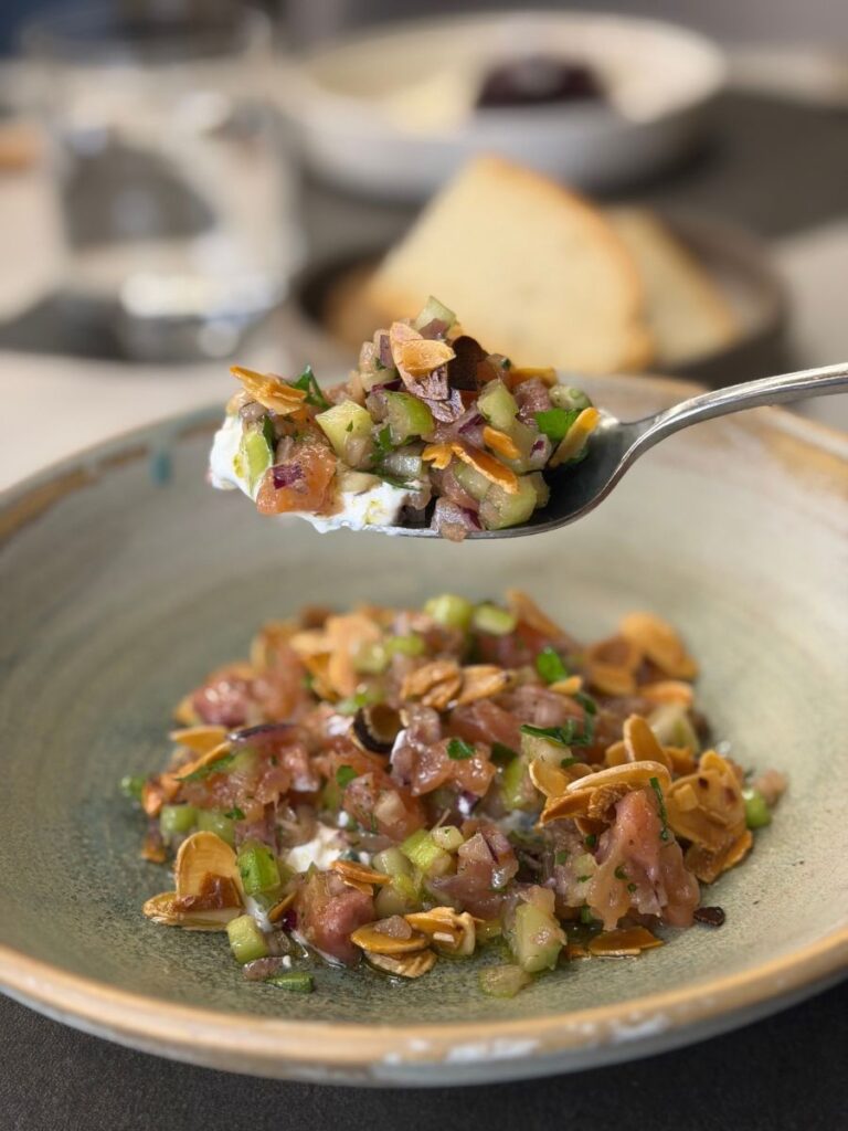 Ceviche di trota servito con mandorle e verdure croccanti in un piatto raffinato