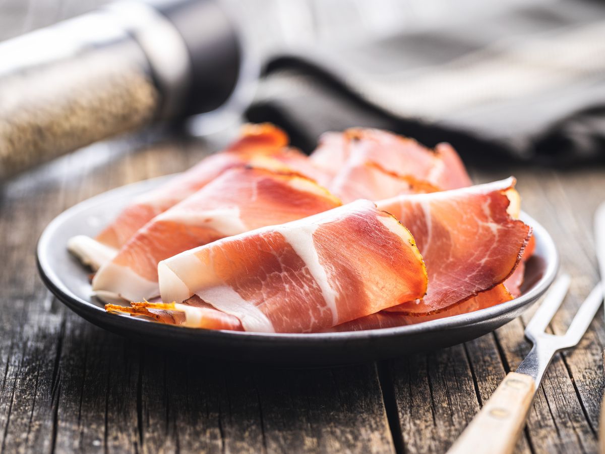 Fette di prosciutto grigio del Casentino disposte su un piatto da portata in ceramica scura.