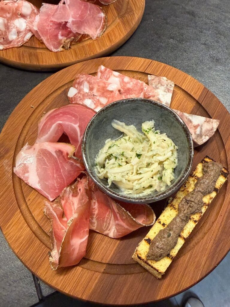 Tagliere di salumi tipici con Prosciutto Grigio del Casentino, crostino di fegatini e contorno in ciotola.